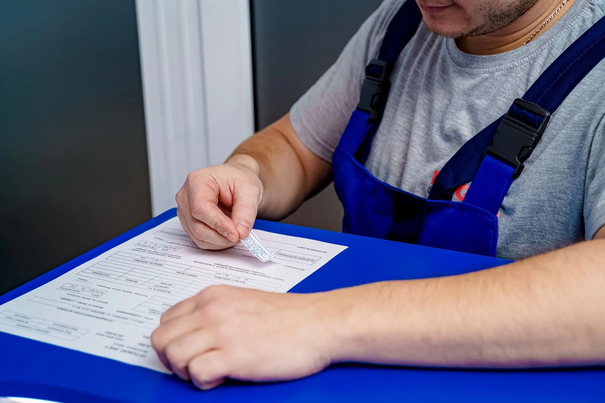 Werkman in overall vult een officieel formulier in aan tafel