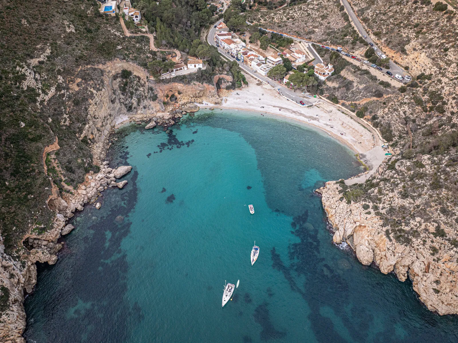Een baai met turquoise water en boten aan de kust van Jávea (Costa Blanca)