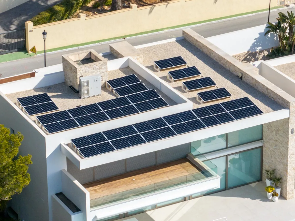 Glas-glas zonnepanelen op stelframes op het platte dak van een moderne villa in Benidorm