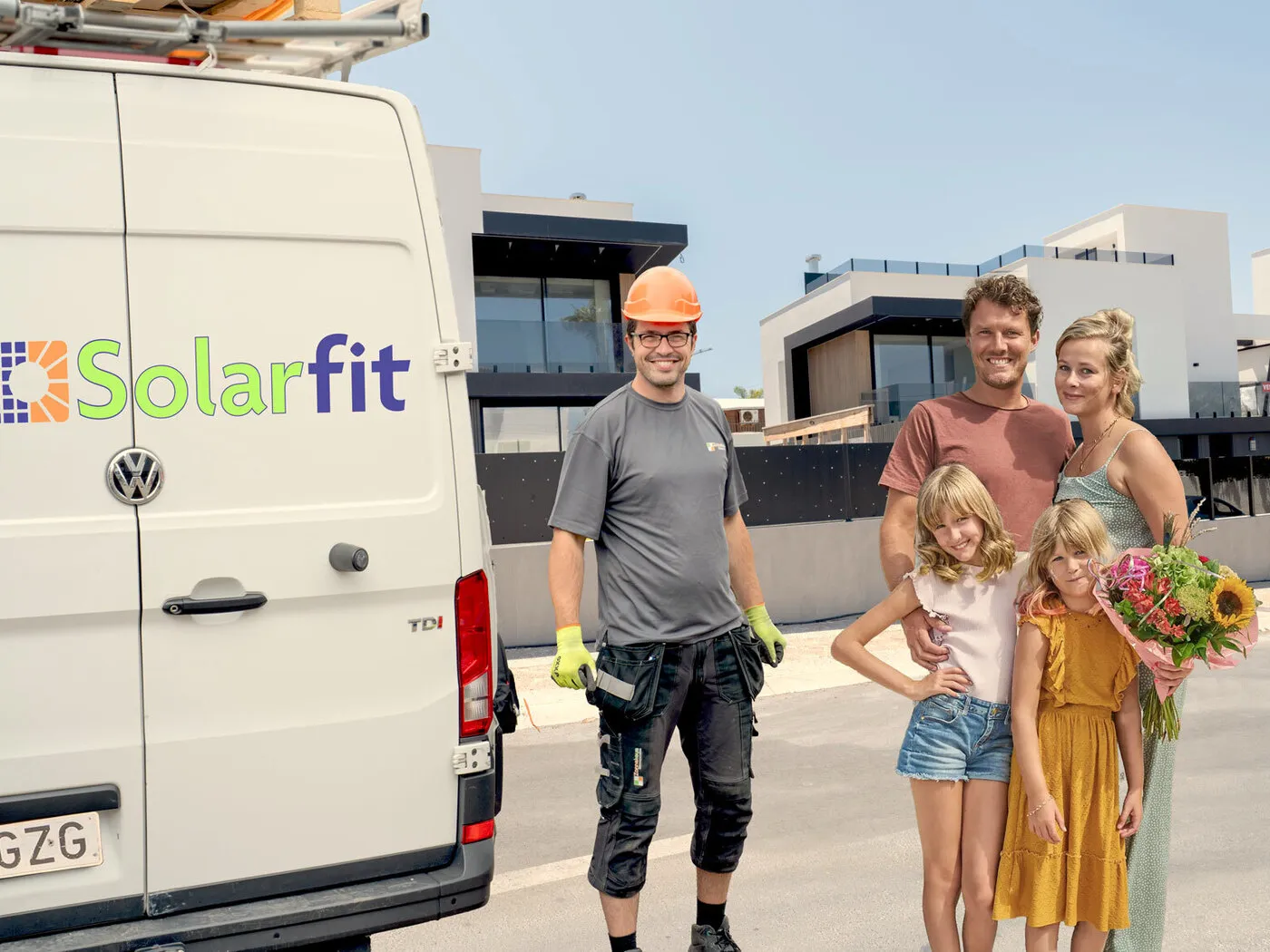 Solarfit-monteur bij de bedrijfsbus naast een tevreden gezin voor hun villa aan de Costa Blanca